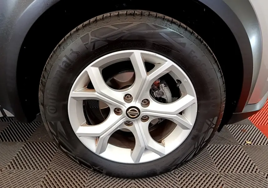 Gros plan sur la roue avant droite du Nissan Juke gris clair 2022 avec jante alliage et pneu Continental.