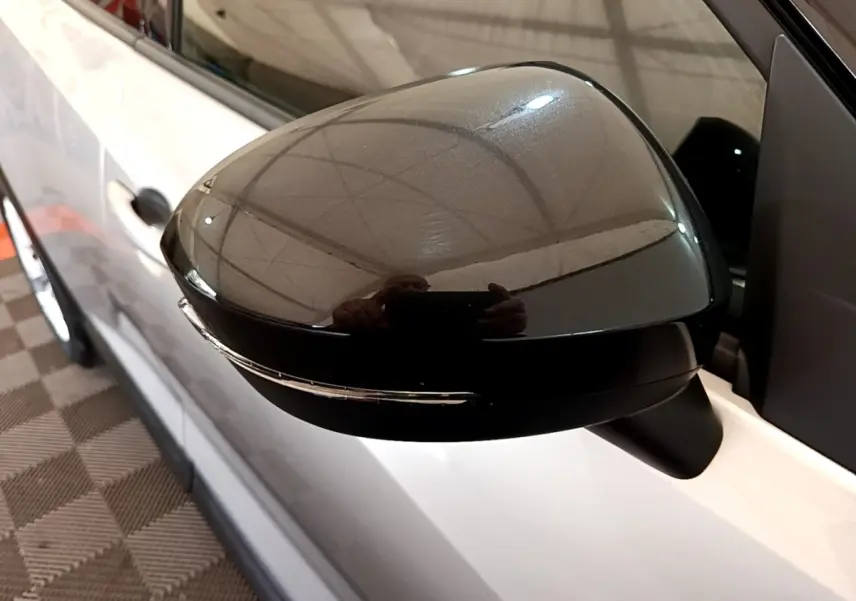 Rétroviseur extérieur droit noir brillant sur Nissan Juke gris clair, vue rapprochée du côté droit.