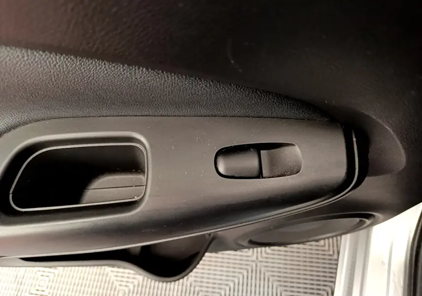 Gros plan sur la poignée intérieure de porte noire du Nissan Juke 2022, côté conducteur, avec bouton de verrouillage.