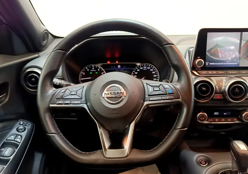Vue intérieure centrée sur le volant cuir noir du Nissan Juke 2022 avec tableau de bord et écran tactile.