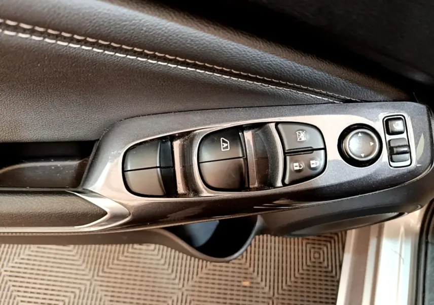 Gros plan sur les commandes de lève-vitres et rétroviseurs côté conducteur d'une Nissan Juke gris clair 2022.