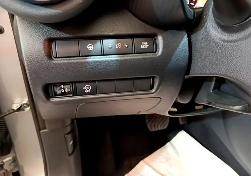 Vue intérieure côté gauche du tableau de bord noir du Nissan Juke gris clair avec commandes de réglage et bouton Trip Reset.