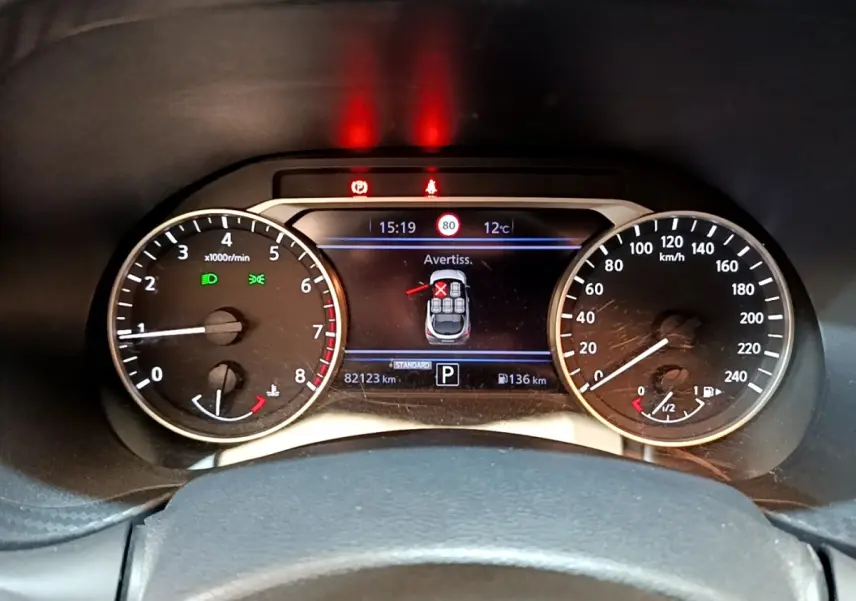 Tableau de bord du Nissan Juke 2022 essence, affichage numérique central avec alertes et compteurs analogiques.