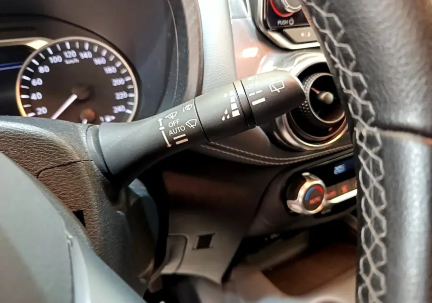 Gros plan sur la manette d’essuie-glace à gauche du volant dans l’habitacle noir du Nissan Juke gris clair 2022.