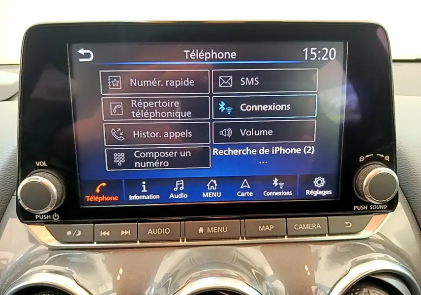 Vue de face du tableau de bord du Nissan Juke gris clair 2022, avec écran tactile multifonctions allumé affichant le menu téléphone.