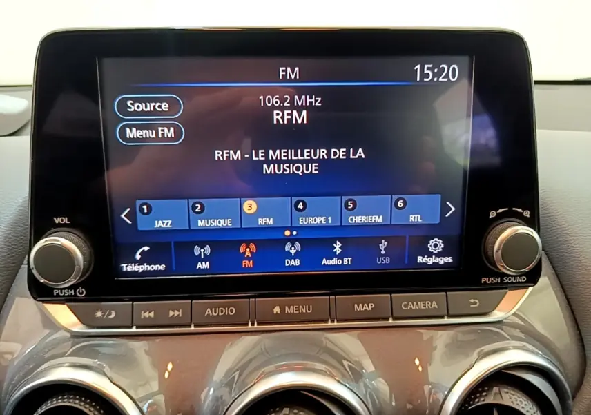 Écran tactile central du tableau de bord du Nissan Juke gris clair, affichant la radio FM à 15h20.