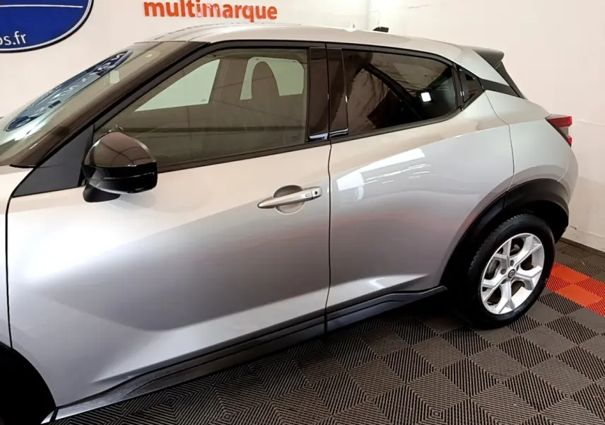 Vue latérale droite d'un Nissan Juke gris clair 2022 avec rétroviseurs noirs et jantes alliage visibles.