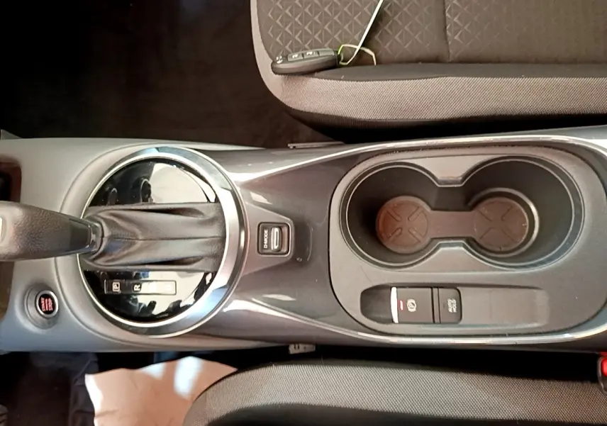 Vue plongeante sur la console centrale noire du Nissan Juke gris clair, avec levier de vitesse automatique et porte-gobelets.