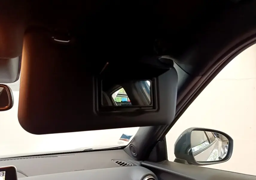 Vue intérieure du pare-soleil côté conducteur avec miroir, rétroviseur extérieur gris clair du Nissan Juke 2022.