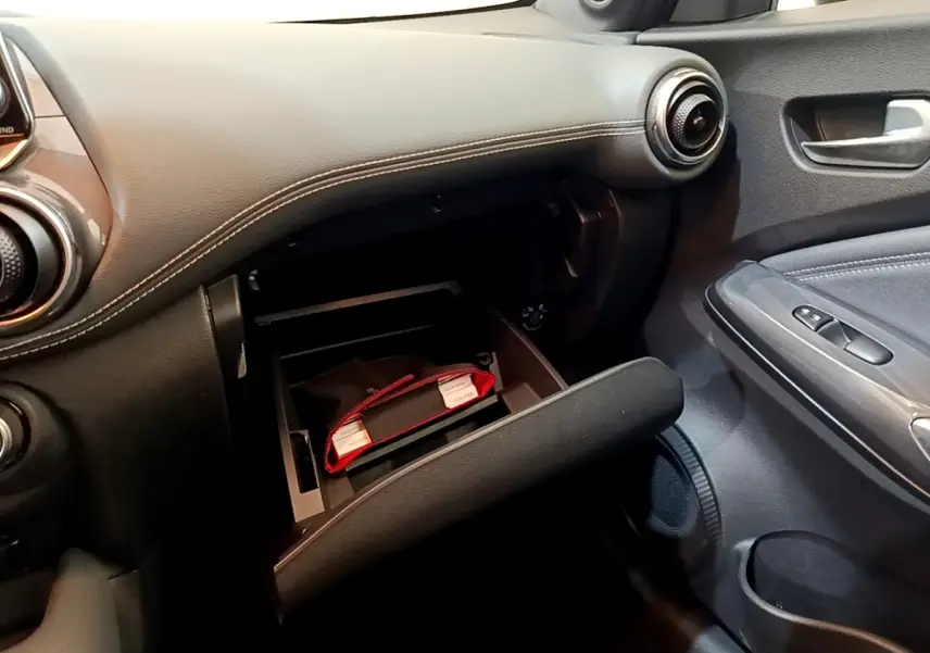 Vue intérieure côté passager du tableau de bord noir avec boîte à gants ouverte du Nissan Juke 2022.