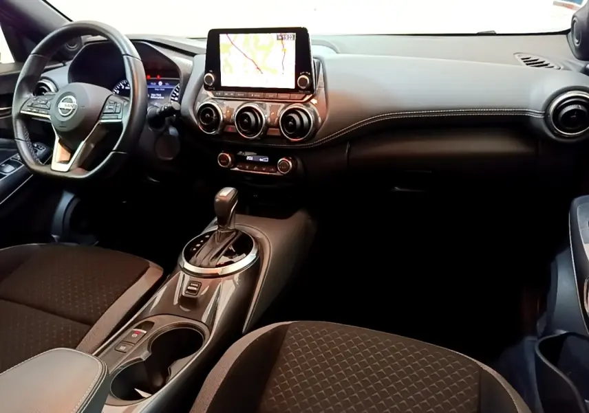 Intérieur du Nissan Juke 2022 gris clair vu de face, avec écran tactile central et console de boîte automatique.