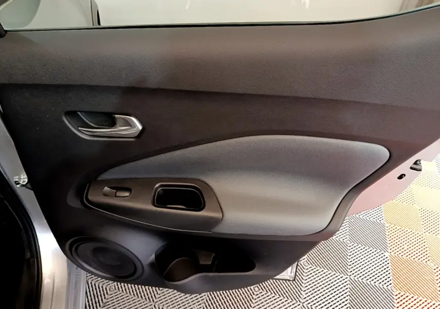 Vue rapprochée de la porte avant gauche gris clair du Nissan Juke 2022 avec poignée et haut-parleur intégrés.