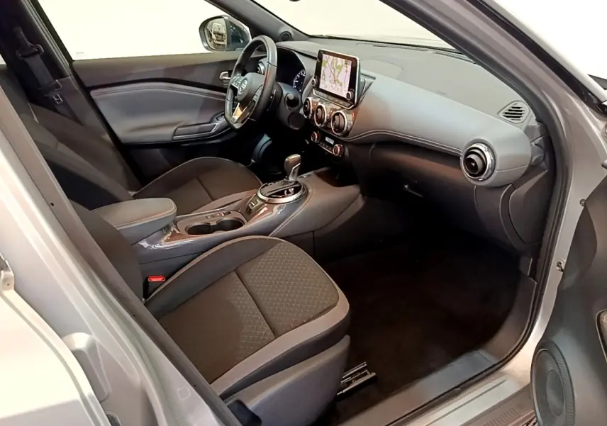 Intérieur avant droit du Nissan Juke gris clair 2022, avec tableau de bord moderne et écran tactile central.