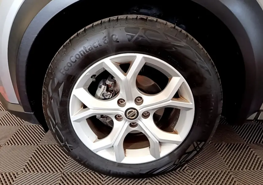 Gros plan sur la roue avant droite d'un Nissan Juke gris clair, avec passage de roue et partie basse de la carrosserie visibles.