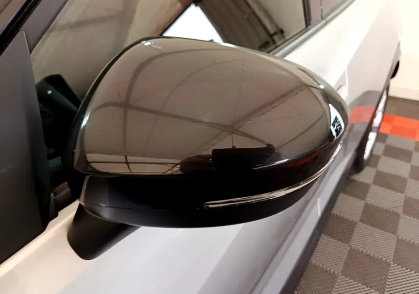 Gros plan sur le rétroviseur droit noir brillant du Nissan Juke gris clair, avec clignotant intégré visible.