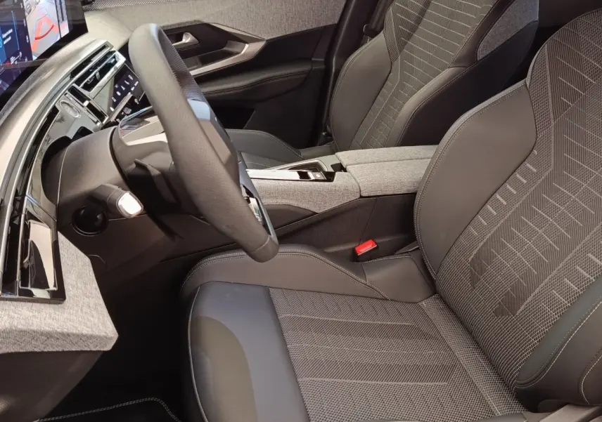 Vue intérieure côté conducteur du Peugeot 3008 Hybrid 2025, sièges tissu et cuir gris avec volant multifonctions cuir.