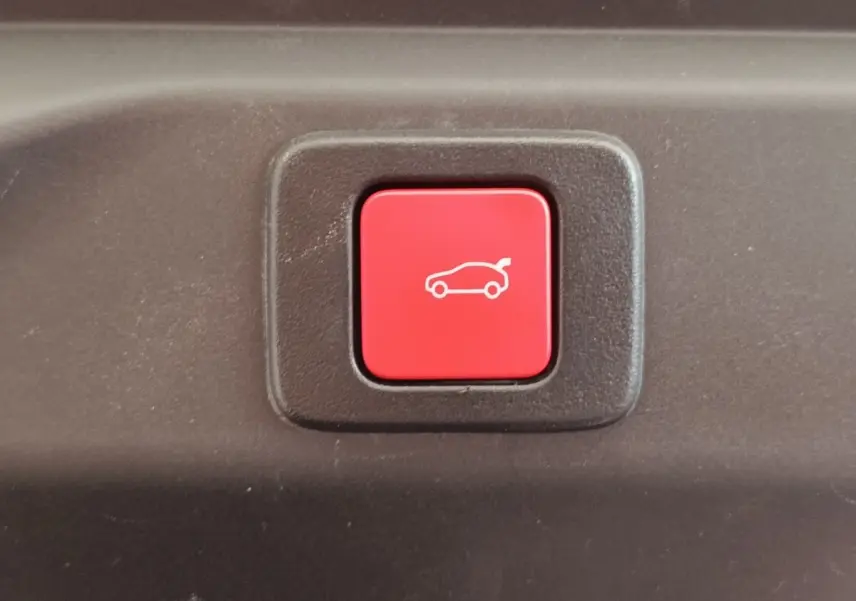 Bouton rouge d'ouverture électrique du coffre sur un Peugeot 3008 1.2 Hybrid 136 E-DCS6 GT, vue rapprochée.
