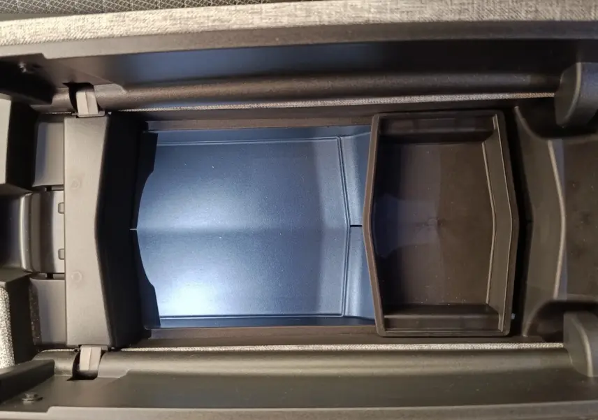 Vue plongeante sur le rangement central intérieur du Peugeot 3008 1.2 Hybrid 136 GT, avec compartiment bleu et noir.