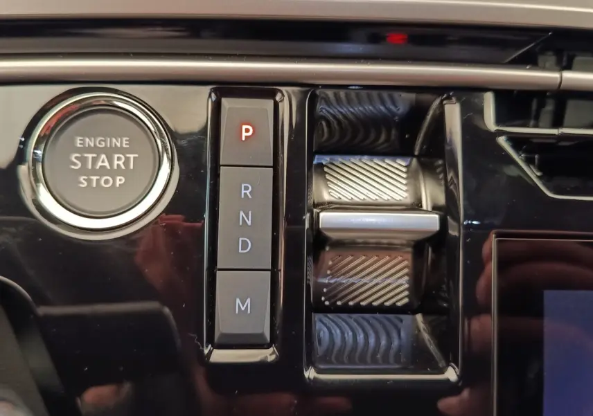 Gros plan sur la console centrale noire brillante du Peugeot 3008 1.2 Hybrid avec bouton start/stop et commande de boîte automatique.