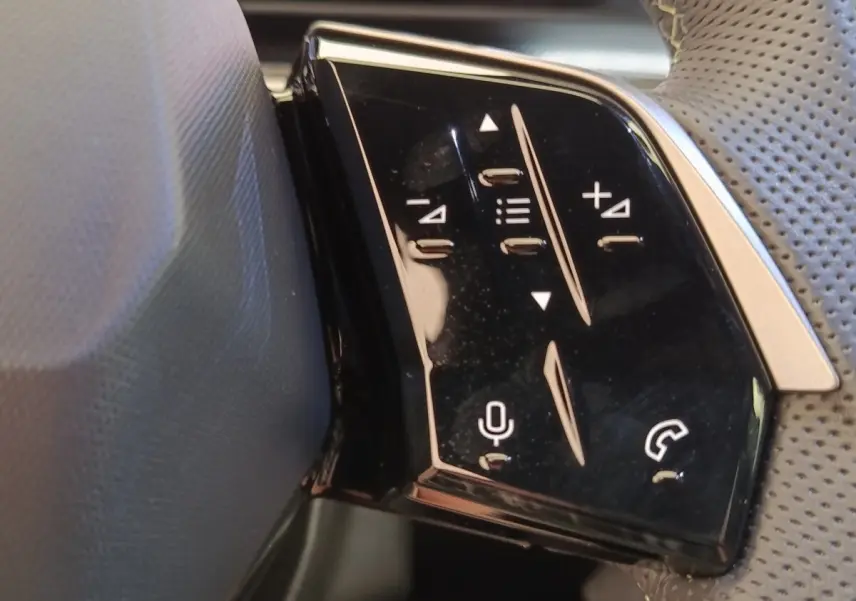 Détail des commandes multifonctions sur le volant cuir perforé du Peugeot 3008 hybride bleu, vue de côté droit.