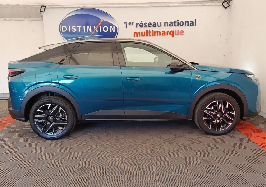 Profil droit du Peugeot 3008 hybride bleu 2025 avec jantes noires et toit noir, en intérieur showroom.