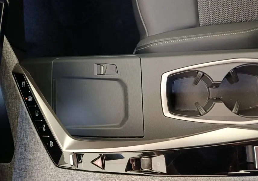 Vue rapprochée de la console centrale grise et noire du Peugeot 3008 1.2 HYBRID 136 E-DCS6 GT avec porte-gobelets.