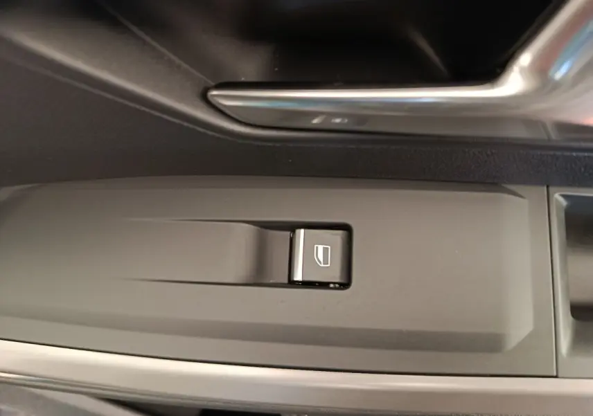 Gros plan sur le bouton de commande de lève-vitre côté conducteur dans l’habitacle du Peugeot 3008 bleu 2025.