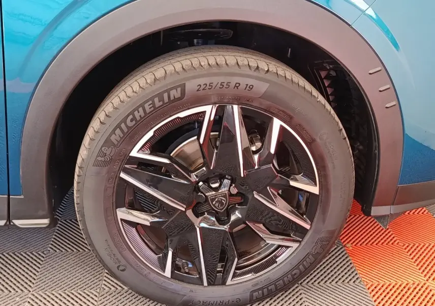Gros plan sur la roue avant droite du Peugeot 3008 bleu 2025 avec jante noire et détails chromés.
