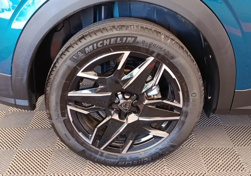 Gros plan sur la roue avant droite d’un Peugeot 3008 bleu, jante alliage noire et argent avec pneu Michelin.