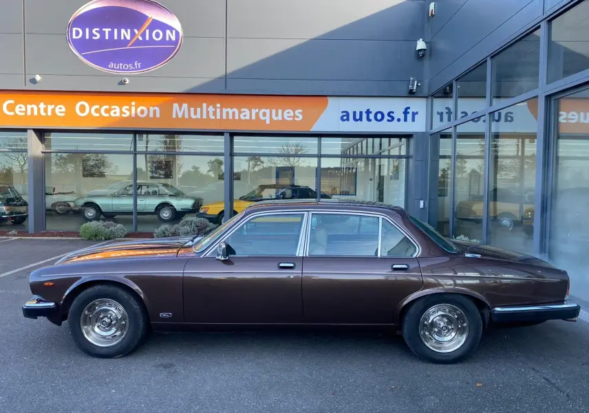 Profil côté gauche d'une Jaguar XJ6 Série 3 4.2 Sovereign marron de 1985 avec jantes chromées et carrosserie lisse.