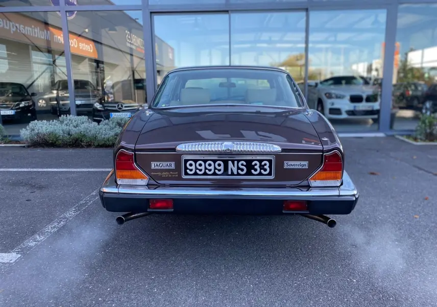 Vue arrière d'une Jaguar XJ6 Série 3 4.2 Sovereign marron de 1985 avec double sortie d'échappement fumante.