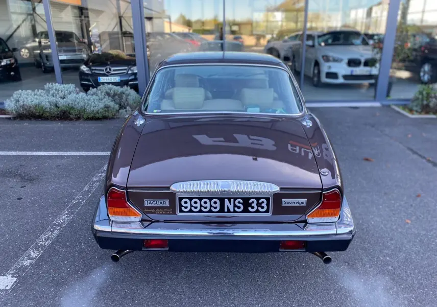 Vue arrière d'une Jaguar XJ6 Série 3 4.2 Sovereign marron de 1985 avec double sortie d'échappement et plaques françaises.