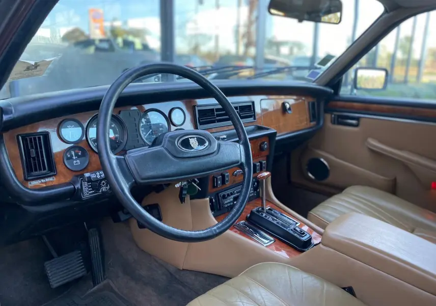 Intérieur beige et bois d'une Jaguar XJ6 Série 3 4.2 Sovereign 1985, vue côté conducteur avec volant et tableau de bord.