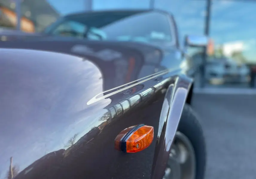 Gros plan sur l'aile avant droite marron d'une Jaguar XJ6 Série 3 4.2 Sovereign 1985 avec clignotant orange.