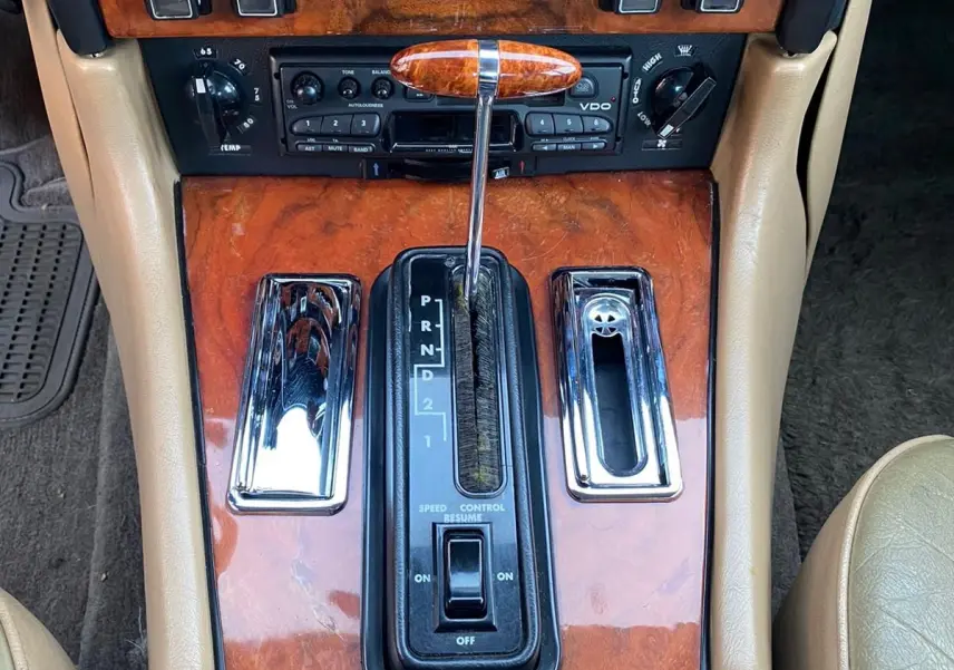 Gros plan sur la console centrale marron en bois verni de la Jaguar XJ6 Série 3 4.2 Sovereign avec levier de vitesse automatique.