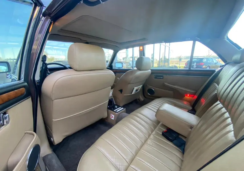 Vue intérieure arrière droite d'une Jaguar XJ6 Série 3 4.2 Sovereign 1985 avec sellerie cuir beige et finitions bois.