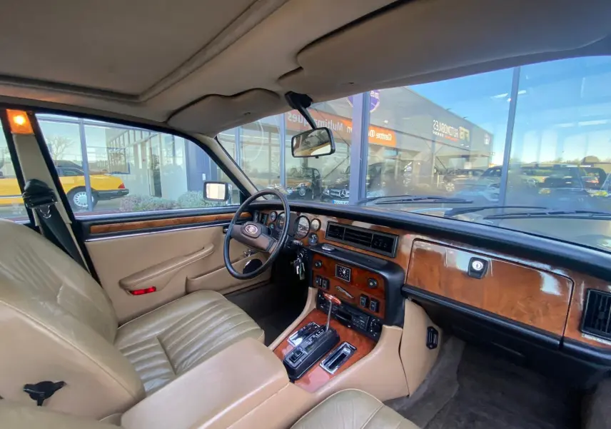 Intérieur beige et bois d'une Jaguar XJ6 Série 3 4.2 Sovereign 1985, vue côté conducteur avec tableau de bord classique.