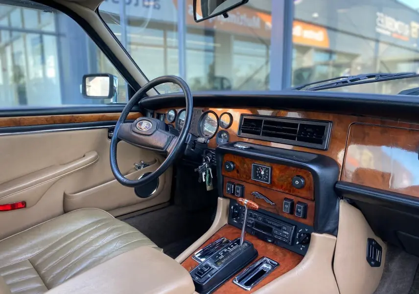 Intérieur beige et bois d'une Jaguar XJ6 Série 3 4.2 Sovereign 1985, vue côté conducteur sur tableau de bord classique.