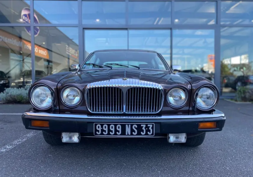 Vue frontale d'une Jaguar XJ6 Série 3 4.2 Sovereign marron de 1985 avec calandre chromée et phares ronds doubles.