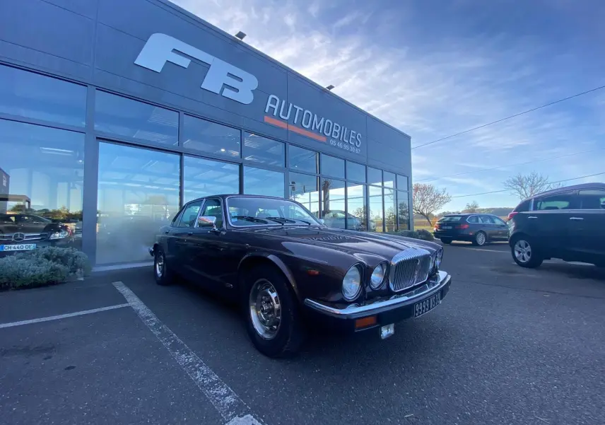 Jaguar XJ6 Série 3 4.2 Sovereign marron vue 3/4 avant droit, garée devant un concessionnaire FB Automobiles.