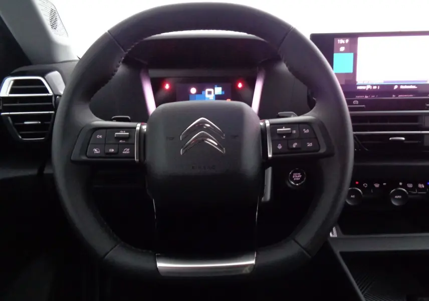 Vue intérieure centrée sur le volant noir du Citroën C4 2023 avec commandes intégrées et tableau de bord digital.