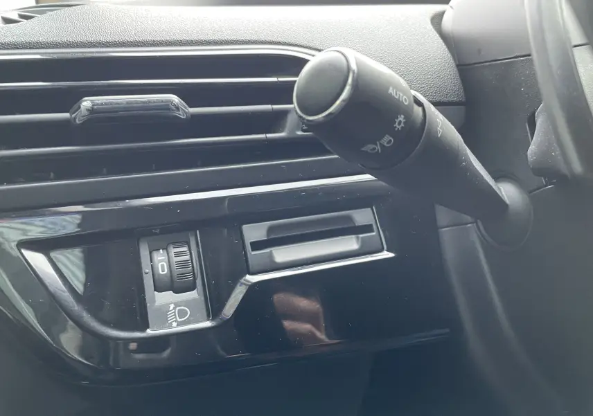 Détail du commodo d'éclairage et de la commande de réglage des phares dans l'habitacle gris du Citroën Grand C4 Picasso 2018.