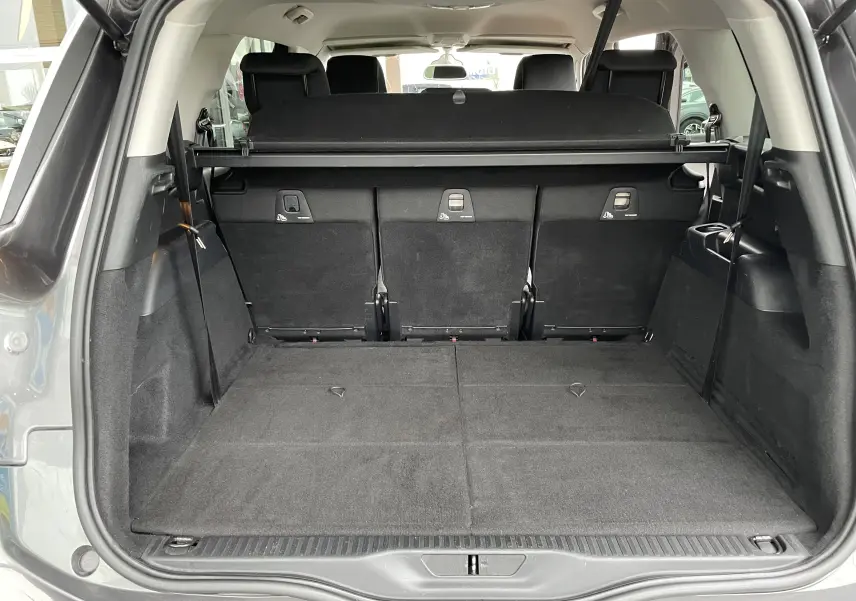 Coffre ouvert du Citroën Grand C4 Picasso gris, vue arrière montrant les sièges rabattus et l'espace de chargement spacieux.