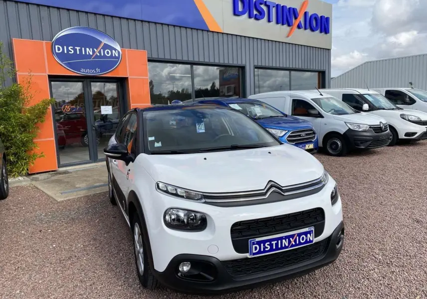 Citroën C3 blanc vue 3/4 avant avec toit noir, stationnée devant un concessionnaire Distinxion.