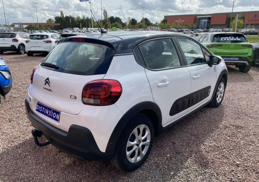 Citroën C3 blanc avec toit noir, vue 3/4 arrière droit, équipée d'un attelage et de protections latérales noires.