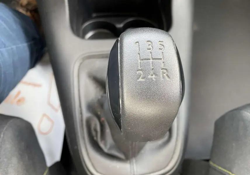 Le levier de vitesses manuel noir de la Citroën C3 blanche vue de dessus, montrant les rapports 5 vitesses plus marche arrière.