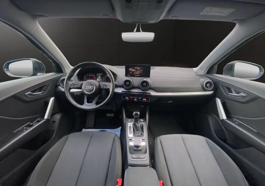 Intérieur noir de l'Audi Q2 2023 vu de face, avec tableau de bord moderne et écran central tactile.