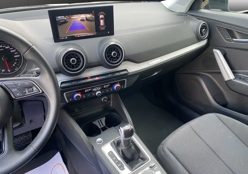 Vue intérieure côté passager de l'Audi Q2 35 TFSI S-Line 2023 avec écran caméra de recul et sellerie tissu noire.