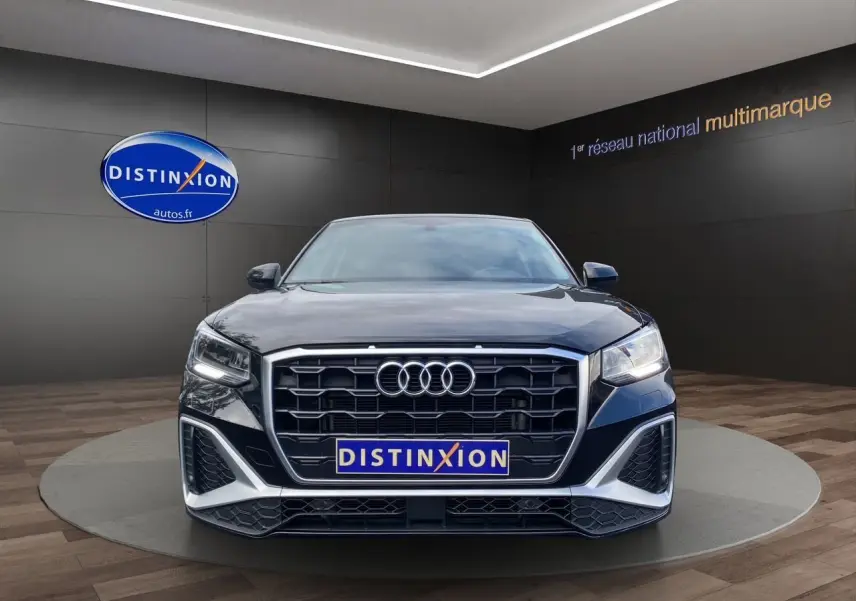 Audi Q2 noir mito vue de face dans un showroom avec calandre hexagonale et feux LED allumés.