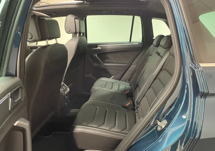 Vue intérieure côté droit des sièges arrière en cuir noir du Volkswagen Tiguan 2024 Nightshade Blue, avec porte ouverte.